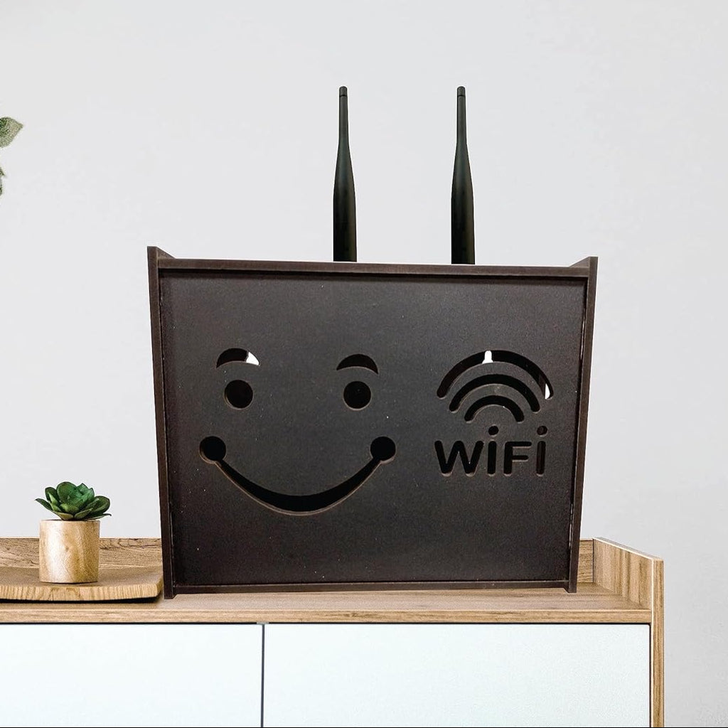 Black WiFi router with smiley face design on a wooden shelf with plants in the background